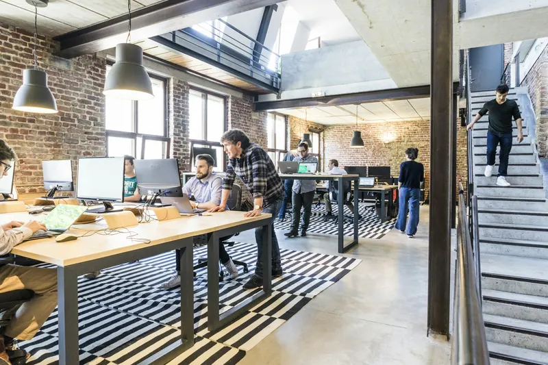 A bright open-plan workspace where a team collaborates around a long table