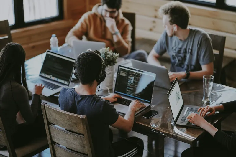 A team collaborating on laptops at a shared wooden table